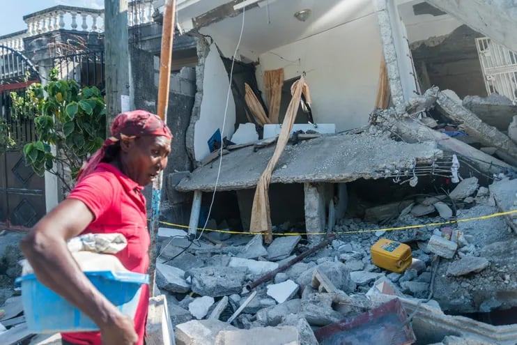 Una mujer pasa frente a una casa destruida en Les Cayes, Haití.