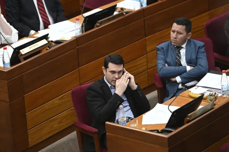 Hernán Rivas  (ANR) habla por teléfono en la sesión de la Cámara de Senadores. Lo mira su colega "Chaqueñito".