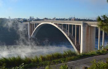 Imagen del Puente de la Amistad en un día de frío polar. La niebla flota del río Paraná y colorea el espacio circulante de la pasarela más reconocida de la frontera.