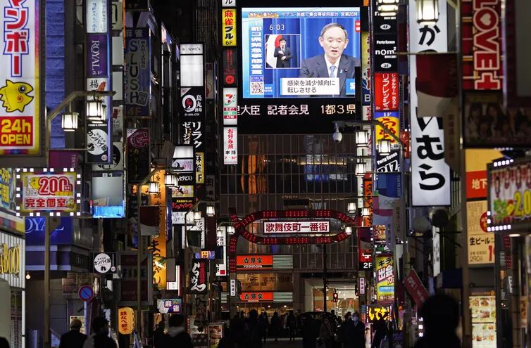 La televisión japonesa muestra en una pantalla gigante del barrio  Kabukicho al primer ministro Yoshihide Suga anunciando el estado de emergencia durante una conferencia de prensa.