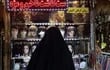 Una mujer con velo observa la vidriera de un negocio donde se venden pelucas en Teherán, la capital de Irán.