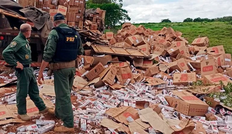 Agentes de la Policía Rodoviaria brasileña observan el cargamento de cigarrillos desparramados.