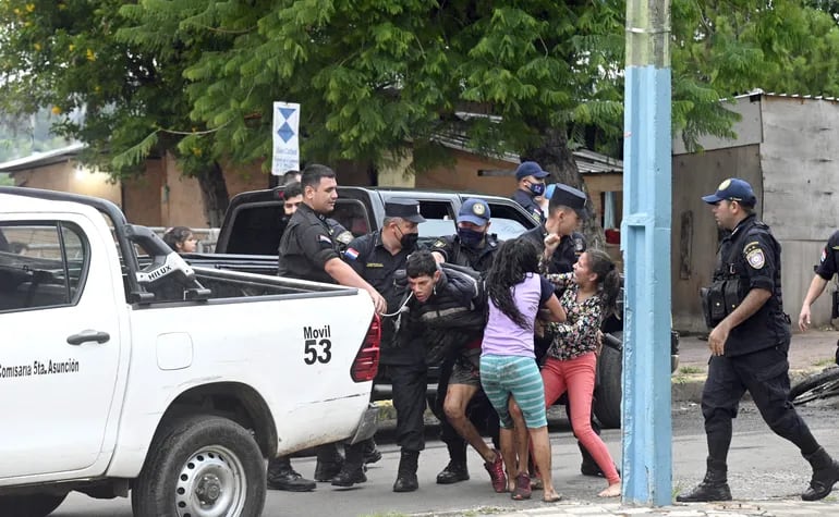 Agentes policiales de la comisaría 5° de Asunción tratan de alzar en la patrullera a uno de los protagonistas de la trifulca, mientras sus allegadas tratan de impedir el arresto. Fue esta tarde frente al Cabildo.