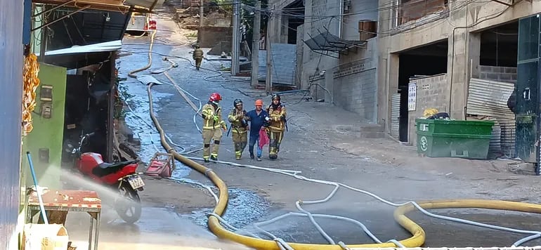 El trabajador rescatado sale caminando de la zona del incendio con ayuda de bomberos.