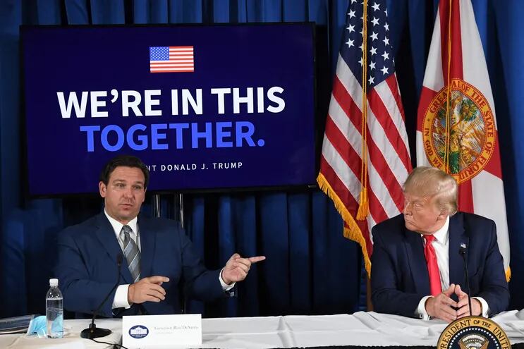 (FILES) US President Donald Trump (R) and Florida's governor Ron DeSantis hold a COVID-19 and storm preparedness roundtable in Belleair, Florida, July 31, 2020. Florida Governor and 2024 Republican presidential hopeful Ron DeSantis has dropped out of the US presidential campaign and endorsed former US president Donald Trump, DeSantis announced in a video posted to his X (formerly Twitter) account on January 21, 2024. (Photo by SAUL LOEB / AFP)