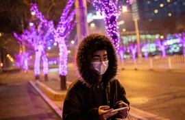 Un hombre con un tapabocas camina en la zona de Sanlitun, en Pekín (China).