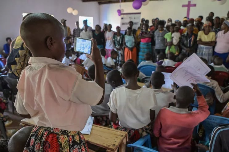 Una niña graba con un teléfono la ceremonia de rito de iniciación alternativa organizada por Manga HEART, una organización sin fines de lucro que lucha contra la violencia de género y la mutilación genital femenina (MGF) en Kisii.