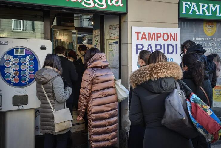 Un grupo de personas forma fila frente a una farmacia en Milán, para someterse a una prueba de Covid.