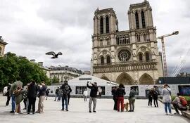 Los turistas toman fotografías frente a la Catedral de Notre Dame, en París, Francia.