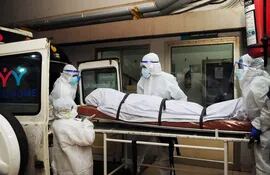 En esta fotografía tomada el 12 de septiembre de 2023, trabajadores sanitarios con equipo de protección mueven el cuerpo de una persona que murió a causa de una infección por el virus Nipah en un hospital privado de Kozikode, en el estado indio de Kerala.
