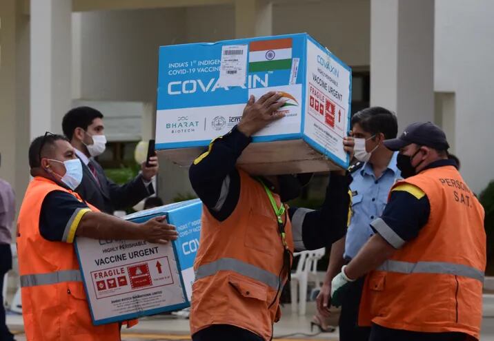 Cajas conteniendo 100.000 dosis de la vacuna india Covaxin contra el COVID-19, donadas por la India, son desembarcadas por trabajadores del aeropuerto Silvio Pettirossi el lunes 29 de marzo.