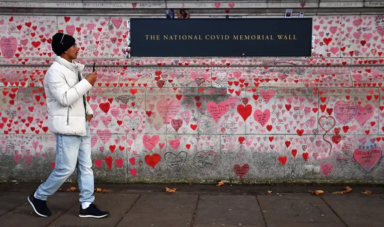 Un hombre camina junto a un muro que rinde tributo a las personas que fallecieron por Covid-19 , en Londres, Inglaterra.