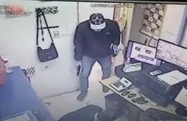 Captura de pantalla de las imágenes del circuito cerrado de la boca de cobranza asaltada en donde se ve a uno de los ladrones con un arma de fuego al reducir a un empleado.