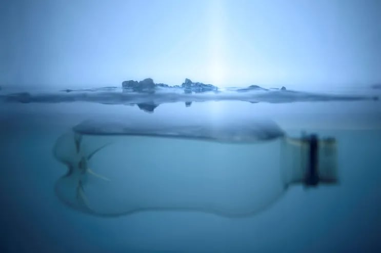 Botella de plástico flotando debajo de una capa de hielo.