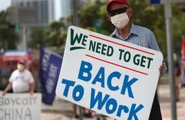 Un manifestante con un cartel que reza "Necesitamos volver a trabajar" protesta contra las medidas de cuarentena en Miami, Florida.