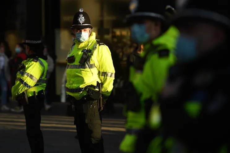 Policías con mascarillas custodian una marcha de personas opuestas a las medidas de restricción contra el covid-19 en Londres.