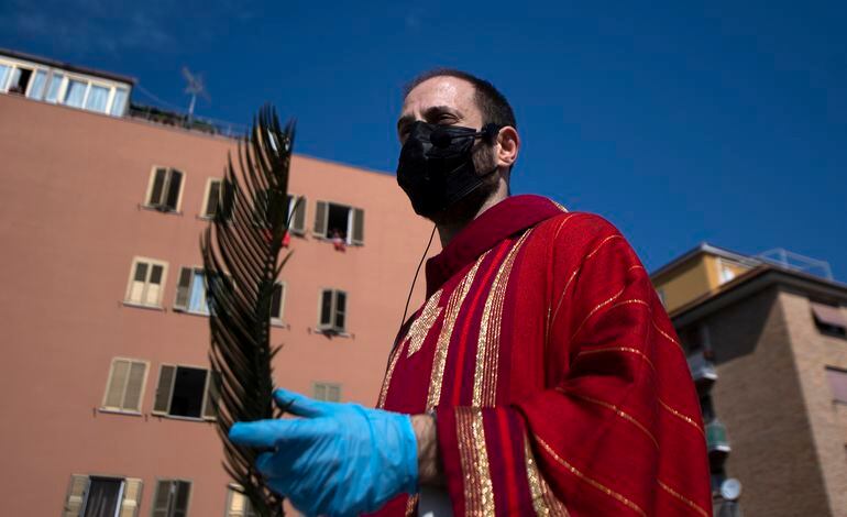 Un sacerdote con tapabocas se prepara para celebrar una misa desde el techo de una iglesia en Roma, Italia.