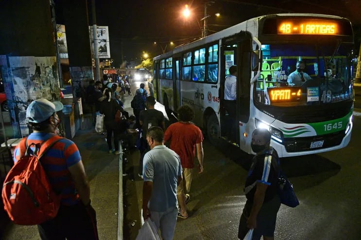 Pasajeros esperan colectivo en los alrededores de la Terminal de Ómnibus de Asunción para retornar al hogar, durante una noche de regulada del transporte público.