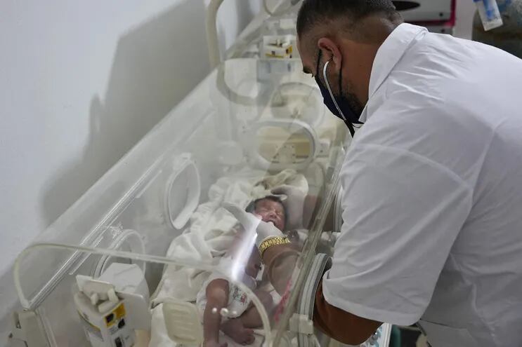 Un médico asiste a la recién nacida que fue encontrada unida al cordón umbilical de su madre, tras el terremoto que azotó a varias localidades sirias.  (AFP)