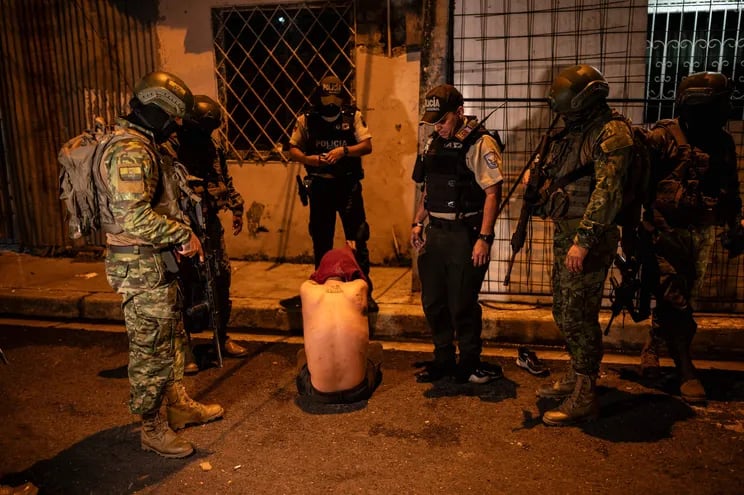 Soldados de la Quinta Brigada de Infantería mantienen detenido a un hombre mientras participan con agentes de policía en una operación de seguridad y buscan sospechosos durante el toque de queda en barrios pobres de Guayaquil, Ecuador, en la madrugada del 12 de enero de 2024.