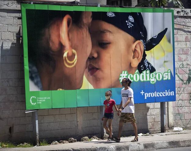 Un hombre y su hija pasan caminando frente a una valla que hace parte de la campaña por el Sí en el referendo sobre el código de familia, en La Habana.