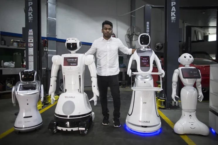 Aswin Sarang, directivo de Reliable Robotics, posa junto a robots que detectan fiebre e higieniza manos en Dubai, Emiratos Árabes Unidos.