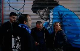 Seguidores del Napoli siguiendo por celulares el desenlace del partido de Lazio vs. Sassuolo, frente a un local con la pintura de Diego Maradona, ídolo máximo de los napolitanos.