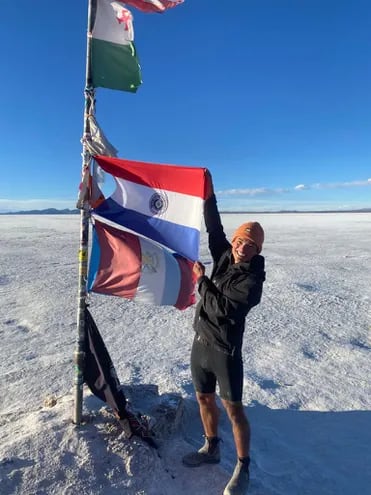 Nico Olmedo (23) sosteniendo la bandera paraguaya en el Salar de Uyuni,. Es norteamericano, hijo de papá paraguayo y siempre tuvo el sueño de conocer nuestro país en bici.