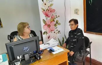 La funcionaria municipal Ángela Attis recibe los documentos de una persona en la secretaría de Adultos Mayores de la Municipalidad de Pilar.