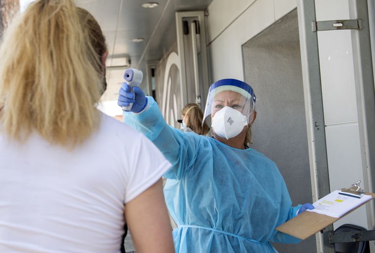 Un trabajador médico revisa la temperatura de una mujer en un sitio de pruebas de COVID-19 en Los Ángeles, California.