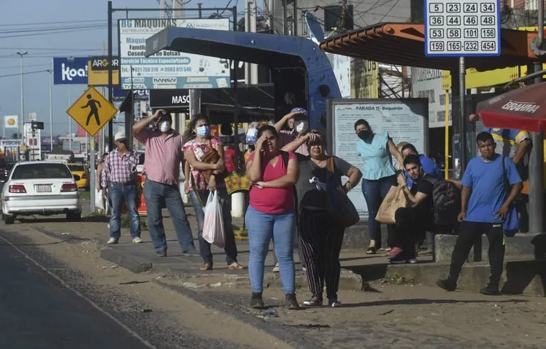 Fotografía de archivo y referencia: personas esperando algún bus en una parada.