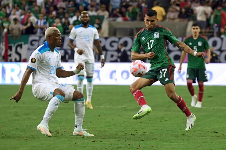 El mexicano Orbelín Pineda (d) lucha por la posesión del balón con el hondureño Deybi Flores, durante el partido que ganaron los aztecas por 4-0.