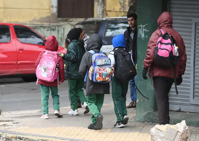 Escolares caminan rumbo a su escuela en un día de frío y llovisna.