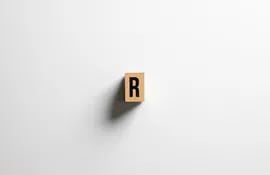 Una ficha de madera con la letra R pintada