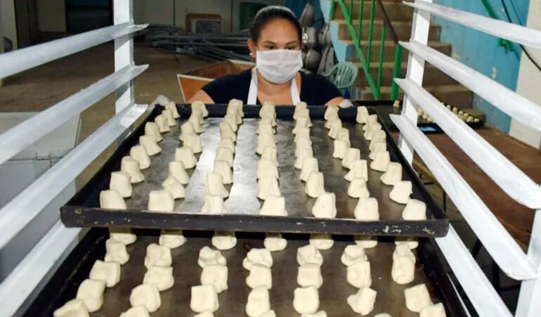 Una operaria de la panadería municipal coloca ordenadamente  las bandejas con la masa para pan para ser llevadas al horno.