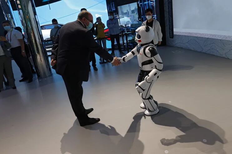 Un nombre saluda con un apretón de manos a un robot panda en el pavellón de China en la Expo Dubai 2020.