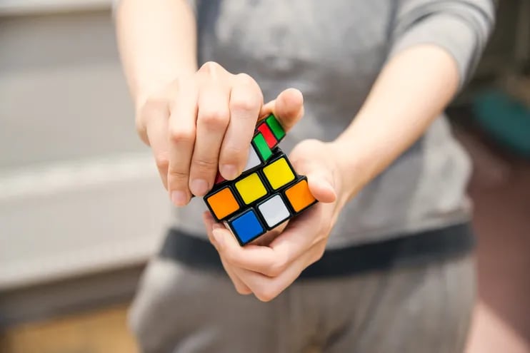 Fotografía de referencia: una persona girando cubo de Rubik buscando igualar sus colores.