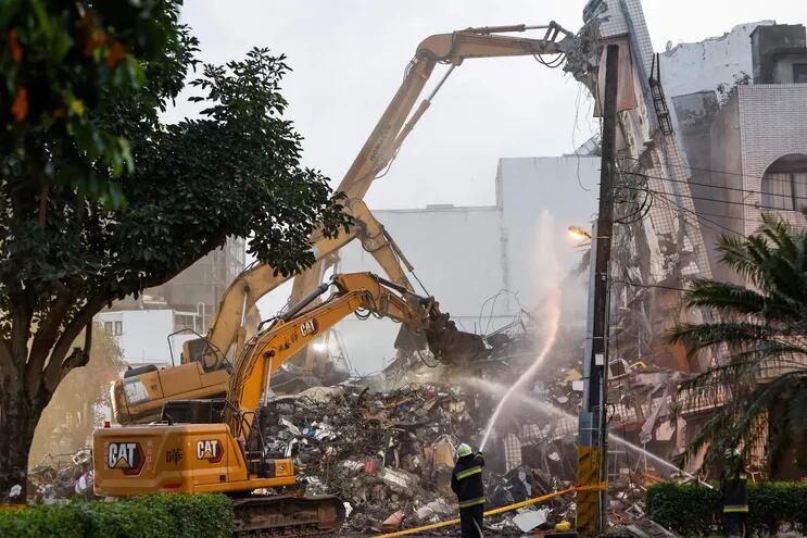 Los bomberos rocían agua mientras las excavadoras demuelen los restos de un edificio residencial derrumbado tras el terremoto de magnitud 7,4 del 3 de abril en Hualien, Taiwán.