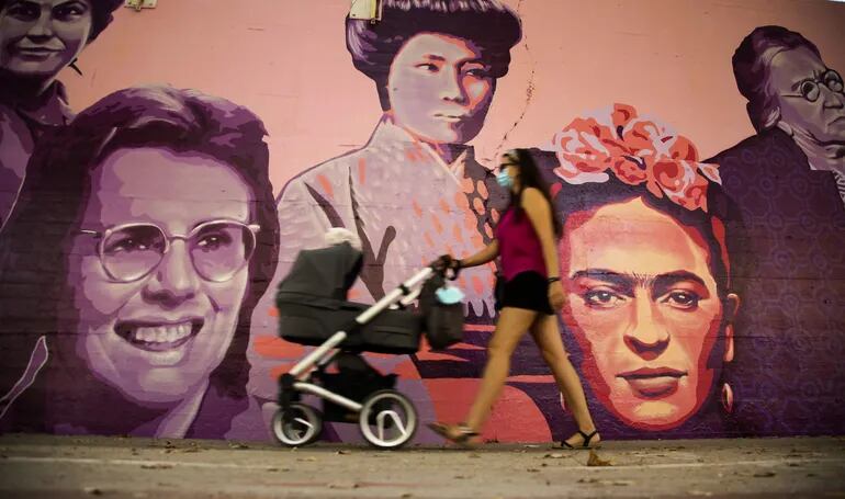 Una mujer camina junto al mural de las mujeres del barrio de Ciudad Lineal en Madrid.