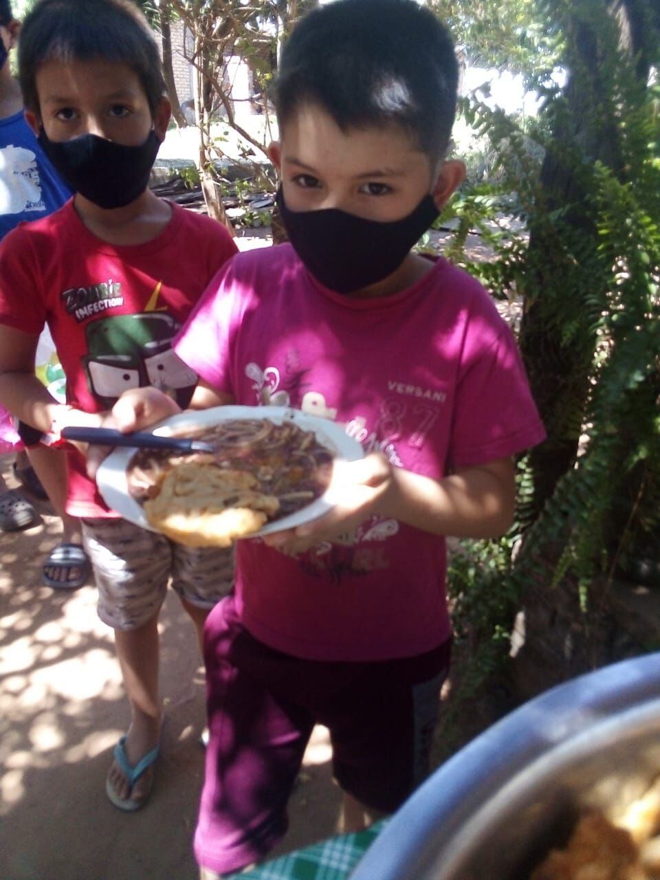 Un niño del asentamiento 24 de agosto de la ciudad de Villeta recibe su plato de comida gracias a las ollas populares que realizan en los diferentes barrios.