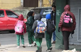 Escolares caminan rumbo a su escuela en un día de frío y llovisna.
