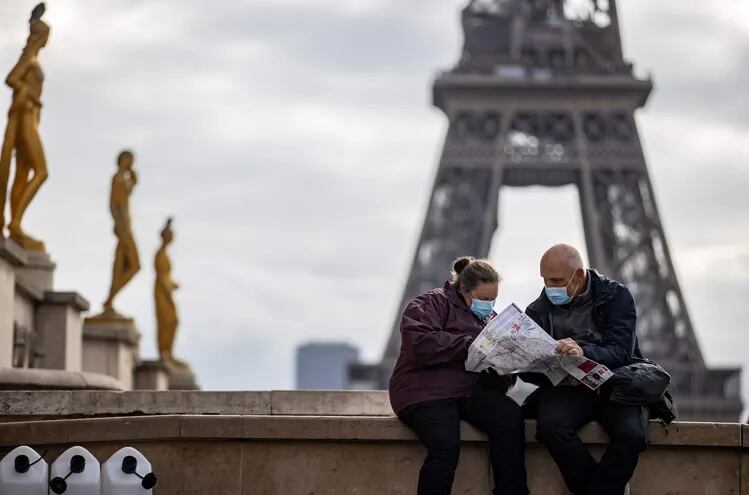 Peatones usan máscaras protectoras mientras miran un mapa cerca de la Torre Eiffel, en París.