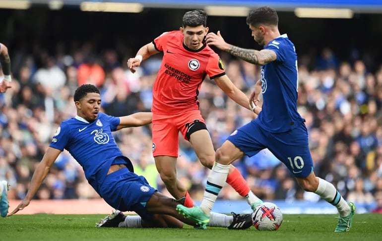 Julio Enciso (c), futbolista del Brighton, domina el balón en medio de Wesley Fofana (i) y Christian Pulisic (d) del Chelsea durante el duelo por la ronda 31 de la Premier League en el estadio Stamford Bridge, en Londres.