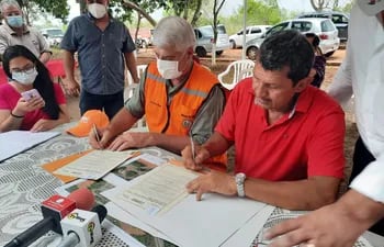 Momento en que el titular del MOPC, Arnoldo Wiens, y el representante de los pobladores de Potrero Kue, Diosnel López, firman el acta de acuerdo de las obras propuestas.
