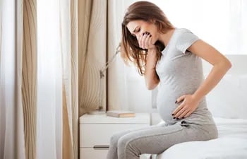 Una embarazada muestra evidentes signos de malestar estomacal.