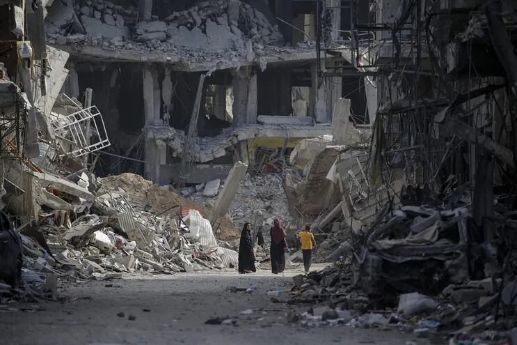 Palestinos caminan entre los edificios destruidos por los ataques del ejército de Israel a la Franja de Gaza.