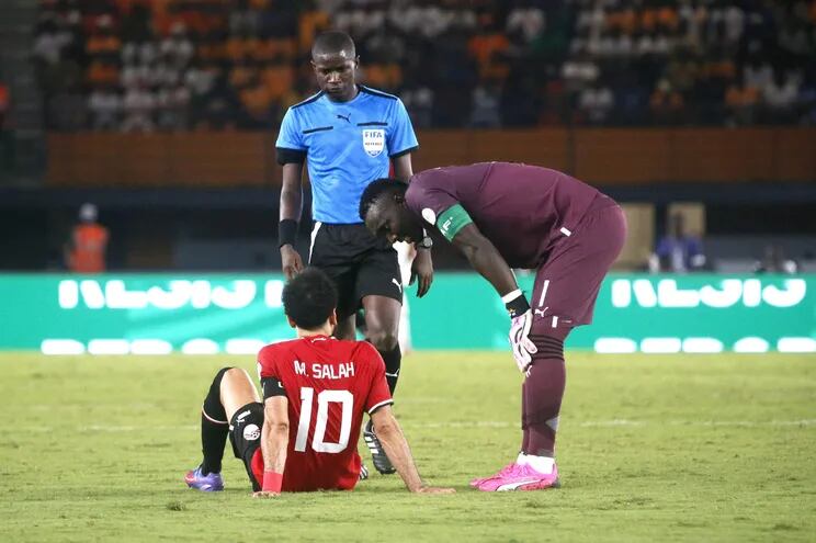 Mohamed Salah se sienta en el céspede del campo, tras sufrir una molestia muscular en el partido que Egipto empató 2-2 con Ghana por la Copa de África.