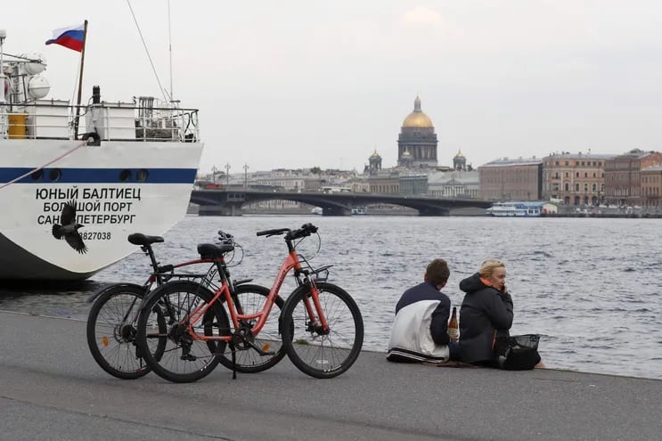 Dos ciclistas descansan luego de un paseo junto al río Neva con la catedral de Isaac de fondo, en San Petesburgo, Rusia.