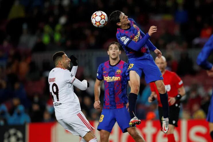 El centrocampista del FC Barcelona, Gavi (d), cabecea el balón ante el jugador marroquí del Benfica, Adel Taarabt, durante el encuentro correspondiente a la fase de grupos de la Liga de Campeones que han disputado hoy martes en el estadio Camp Nou, en Barcelona.