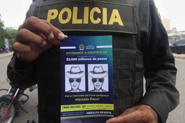 Un policía muestra el volante que identifica al presunto autor material del asesinato del fiscal antimafia paraguayo Marcelo Pecci ayer, en una playa privada de Cartagena de Indias (Colombia).